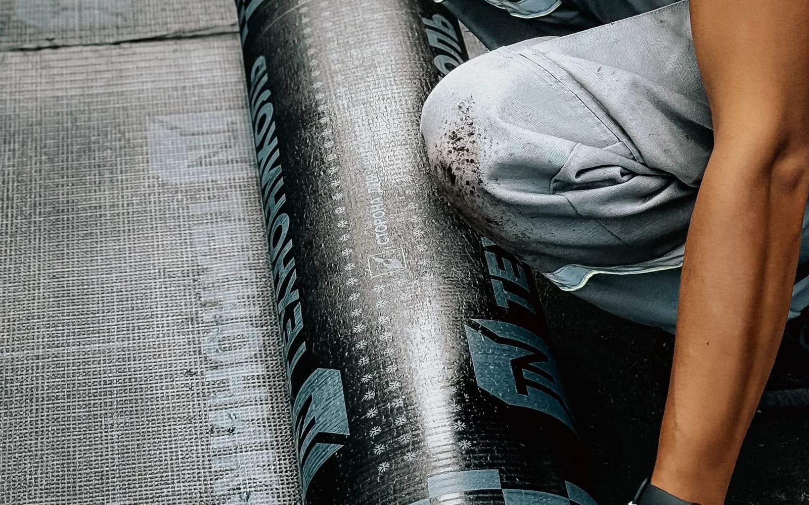 Roofing professional installing a waterproof membrane on a flat roof